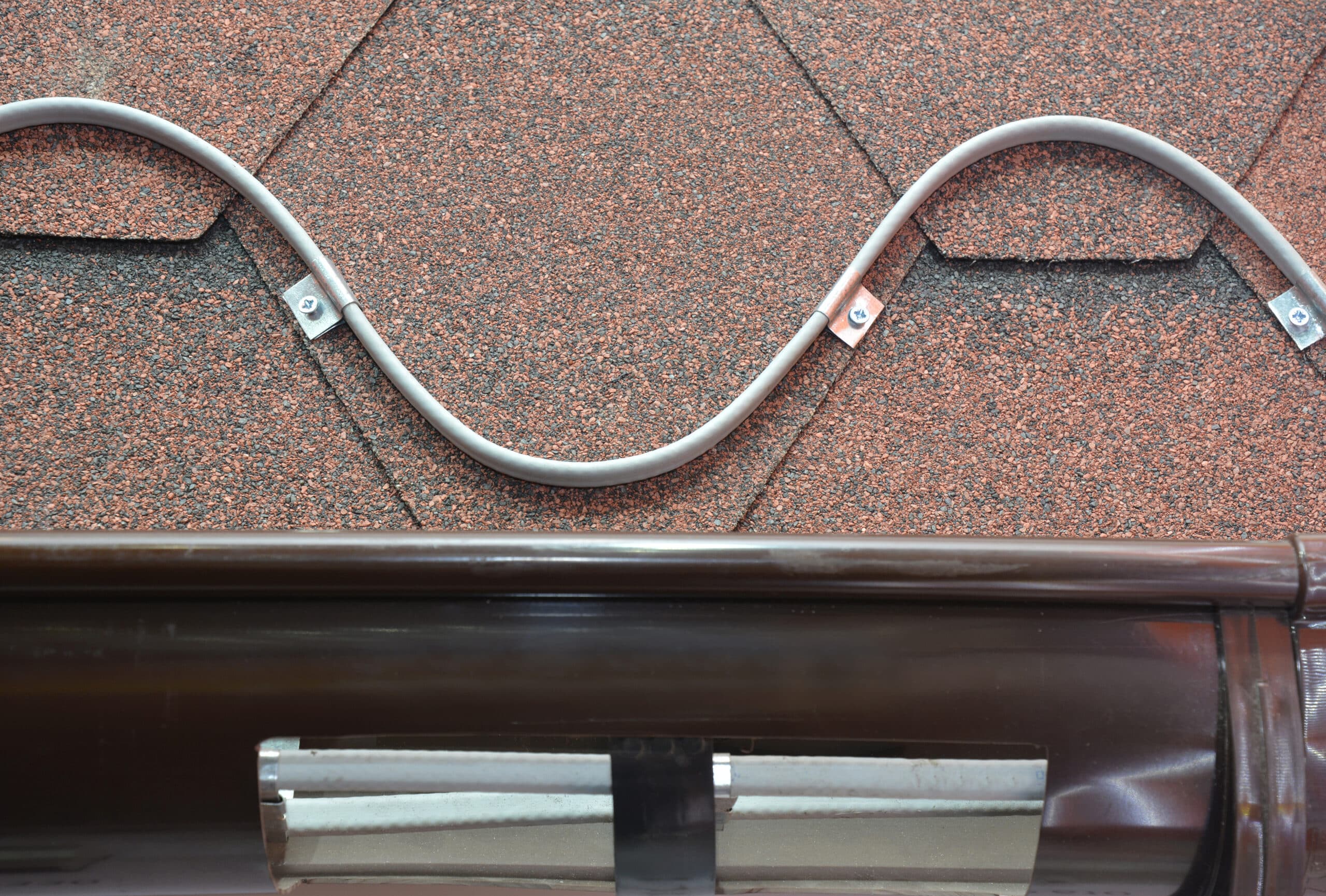 Roofing heating cable for ice and snow melting. A close up on a roofing deicing system, ice melting cable installed above and inside roof gutter